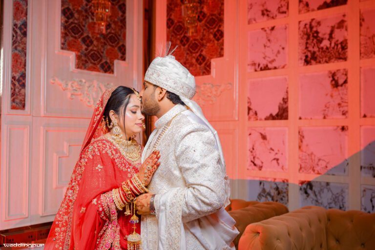 Groom kissing bride on forehead during wedding moment indoors